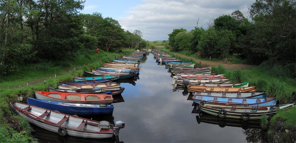 Colourful boats beside a wooded riverbank