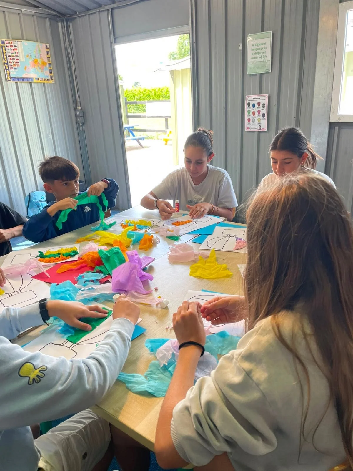 Children creating colourful artwork around a classroom table