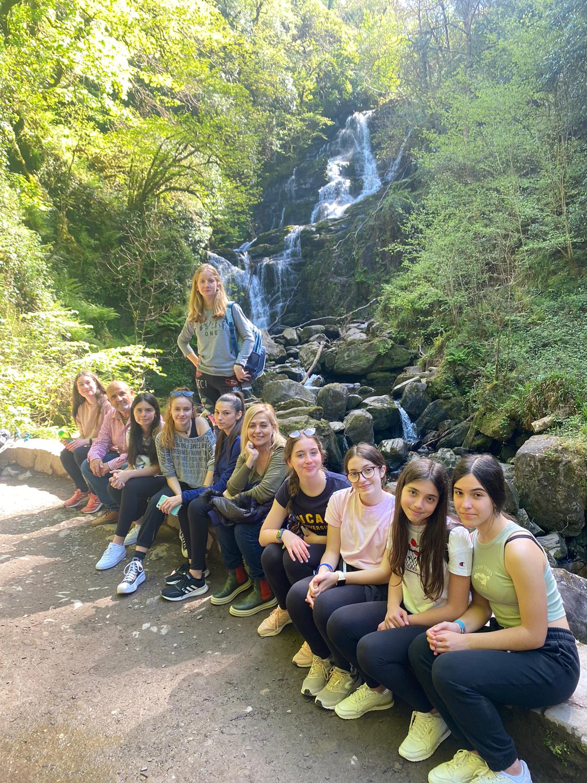 Élèves et adultes en excursion près d’une cascade en forêt