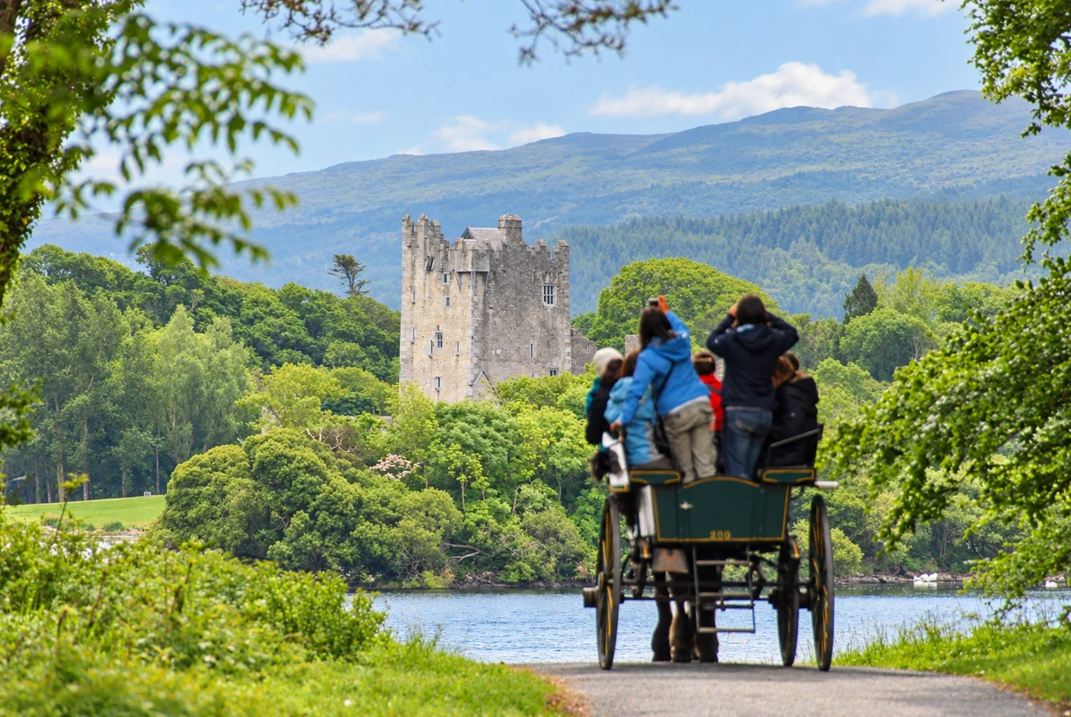 Eine Pferdekutsche nähert sich Ross Castle am See