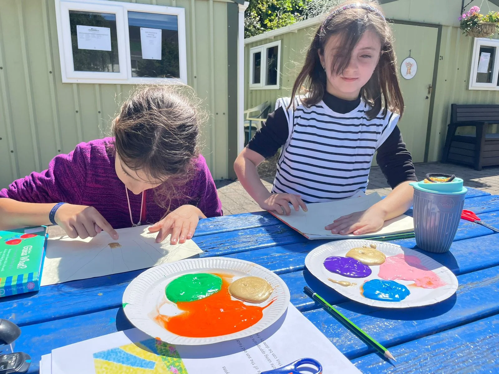 Kidzone 앞 피크닉 테이블에서 그림을 그리는 어린이들