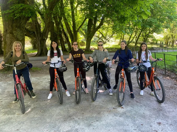 Teenage students cycling together beneath the trees